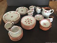 Full view of set showing cups, saucers, plates, bowls, creamer, and pitchers in floral Garland pattern with light terracotta accents.