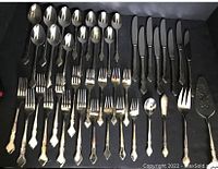 41 pieces of silver plated flatware laid out including knives, forks, spoons, and serving pieces in a fitted box.