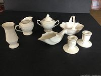 Front angled view showing all 7 white ceramic Lenox pieces in the lot arranged on a black surface.