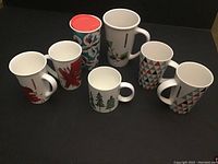 Front view of the seven Starbucks holiday and Christmas mugs and travel cups with various seasonal designs