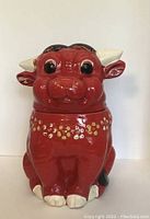 Front view of the red bull cookie jar showing the face, details, and floral patterns around the neck.
