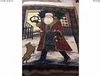 Full view of vintage Santa Claus tapestry throw blanket with Santa carrying a small pine tree and a dog standing nearby on a snowy street scene.