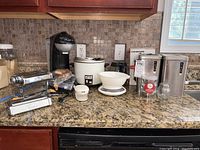 Photo showing kitchen counter with Gevalia coffee maker, Sanyo rice cooker, Marcato manual pasta machine, coffee grinder, kitchen scale with ceramic bowl, vintage metal canisters, and Bodum Chambord press in background.