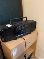 Photo of the JVC portable boombox showing front and side speakers, cassette player, and control buttons.