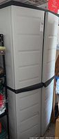 Exterior side view of the white plastic storage cabinet showing closed doors with horizontal panel designs.