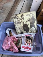 Blue tote containing various nostalgic items including Groucho Marx figurine and Big Boy coin bank in original packaging.