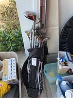 Set of golf clubs in a black golf bag positioned in a garage near various storage items.