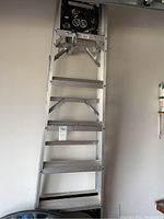 Full view of the 16-foot aluminum extension ladder leaning against a wall, showing the bent rung and metal side rails.