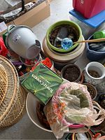 Top view showing wicker basket, ceramic pots with soil, plastic green pot with garden stick, and assorted containers.
