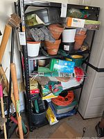 Full view of shelving unit containing pots, boxes, tools, cords and buckets