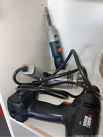 Photo showing Black and Decker 7.2V cordless power drill model 9099KC in black with red trigger and White logo marking on side, connected to power charger.