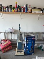 Photo of the vintage Hoover upright vacuum, Bissell Aeroswift boxed vacuum, ladder and garage items.