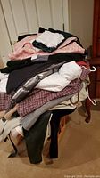Pile of assorted coats and clothes with various fabrics and colors, some on hangers