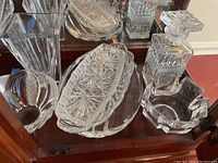 View of the Bohemia decanter with stopper, crystal serving platters, and cut crystal tray inside a cabinet