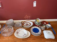 Cut glass plates, German china plates with floral and gold detailing, teacups and saucers, serving bowls and platters arranged on floor