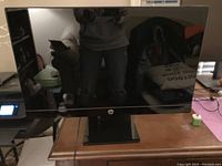 Black HP computer monitor on stand on a wooden table, screen is dark