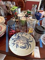 Wide view of assorted kitchenware including ceramic crab platter, various glass tumblers, travel bottles, and ceramic mugs.