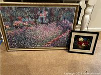 Photo showing the large framed Claude Monet reproduction painting and smaller framed floral print side by side on carpeted floor.