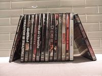 Photo showing 15 DVD cases lined up with titles visible on spines including Traitor, Immortal, Where Eagles Dare, The Girl in Black, The Devil's Game, Hunter 8, Billy Elliot, Larry Crowne, Head State, Cheerleader