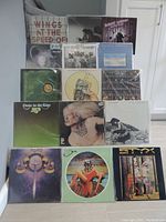 Full lot of 15 mostly 1970s rock vinyl LP records stacked on stairs with cover art visible showing Wings, Robert Gordon, Electric Light Orchestra, Dire Straits among others.