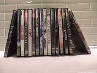 Photo showing 16 DVDs with spines visible, featuring titles such as Salt, Flags of Our Fathers, Godsend, The Exorcism of Emily Rose, Primary Colors, and others.