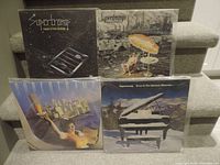Four Supertramp LP covers arranged on steps: 'Crime of the Century,' 'Breakfast in America,' 'Famous Last Words...,' and 'Even in the Quietest Moments...'. Covers show distinct artwork and are in good visible condition.