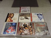 Photo showing seven Christmas music CDs featuring various artists arranged on a flat surface.