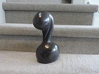 Front view of the black abstract stone sculpture showing its fluid curved design.