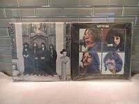 Photo of The Beatles Hey Jude and Let It Be album covers side by side on a countertop with a tiled backsplash.