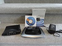 Front view of the Efficient Networks SpeedStream 5200 modem with software CD, user manual, and power adapter placed on carpeted stairs.