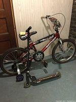 Child’s black and red bike with training wheels next to a black Razor scooter showing overall condition and setup.