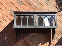 Front view of the blue display shelf showing two doors with arched window panels.
