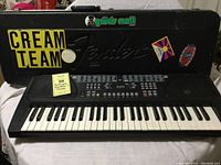 Full view of Huntington keyboard in front of Fender bass guitar carrying case with stickers