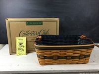 Front view of the Longaberger Welcome Home Basket with the original branded box behind it and a lot tag next to it.