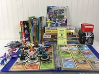Full lot overview showing binders with Pokémon cards, books, boxed card sets, DVDs, and figurines