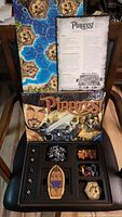 Opened game box showing board with hexagonal island tiles and Pirates! rulebook on top