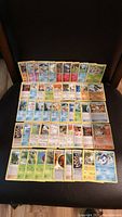 Full layout of 50 Pokémon cards spread out on a dark surface, showing a mix of different Pokémon species and trainer cards.