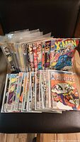 Photo showing an assortment of vintage comic books including X-Men, Avengers, Fantastic Four, and others stacked and protected in plastic sleeves.