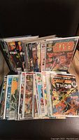 Photo showing a selection of vintage Marvel comic books including Star Wars and Thor titles, arranged in two rows with some comics in protective sleeves.