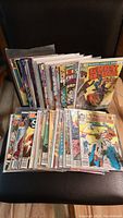 Photo showing a large array of the 50 vintage comic books arranged on a chair, many in protective plastic sleeves.
