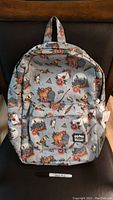 Front view of the gray Harry Potter backpack with various colorful themed prints like roses, broomsticks, magical symbols, and Hogwarts castle.