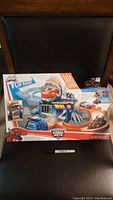 Front view of sealed Transformers Rescue Bots Flip Racers playset in box placed on chair.