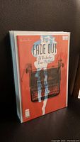 Single comic book issue from The Fade Out series, displayed standing with visible typewriter cover art in orange tones.
