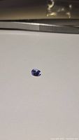 Close-up of a single oval cut lilac purple tanzanite gemstone on a white background.