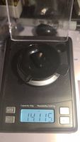 Black onyx gemstone on digital scale showing 14.115 grams weight.