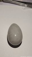 Photo showing polished egg-shaped natural blue selenite stone with light translucent quality.