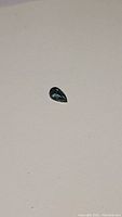 Pear shaped deep blue aquamarine gemstone on neutral background, top view