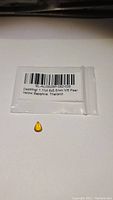 Photo of a small natural golden yellow sapphire in a sealed plastic bag with a label indicating 1.11 carat, 8x5.5 mm, VS clarity, pear shape, from Thailand.