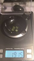 Four small apple green peridot stones on a black weighing device showing total weight 1.915 grams (1.91 carats).
