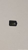 Close-up photo of the emerald cut tourmaline gemstone showing its rectangular shape and reflective facets.